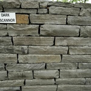 A neatly stacked stone wall with a label reading "DARK LISCANNOR" attached to it.