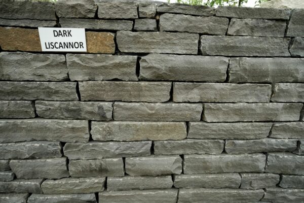 A neatly stacked stone wall with a label reading "DARK LISCANNOR" attached to it.