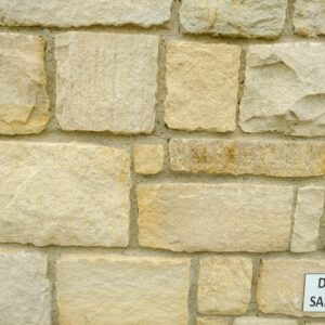 A close-up of a wall made from rectangular blocks of Donegal sandstone, with a label stating "DONEGAL SANDSTONE" attached to the wall.