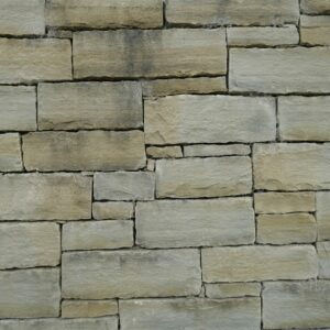 A textured wall made of Kilkenny sandstone blocks neatly arranged in a staggered pattern with a sign indicating the type of stone.