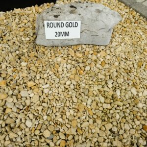 A large pile of round gold 20mm stones with a sign on a rock that reads 'ROUND GOLD 20MM'.