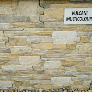 A wall clad with multicolored stone tiles labeled "VULCANI MULTICOLOUR".