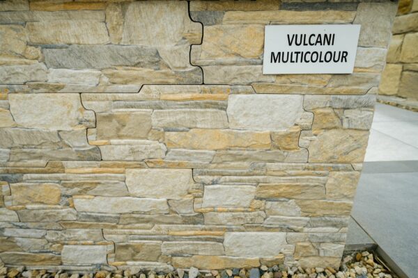 A wall clad with multicolored stone tiles labeled "VULCANI MULTICOLOUR".