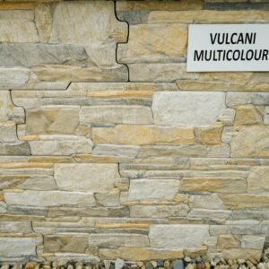 A wall clad with multicolored stone tiles labeled "VULCANI MULTICOLOUR".