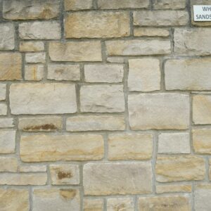 A stone wall made of white sandstone blocks with a label in the top right corner reading "WHITE SANDSTONE."