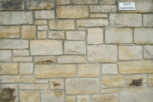 A stone wall made of white sandstone blocks with a label in the top right corner reading "WHITE SANDSTONE."