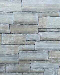 A close-up of a wall with a staggered pattern of rectangular gray stone tiles.