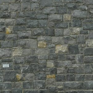 A stone facade on a building with a triangular gable and visible roof eaves, featuring a stone bench near steps on the right side.