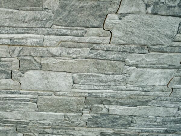 Decorative gray stone wall with a sign that reads "VULCANI GRIGIO" and a bed of multi-colored pebbles at the base.