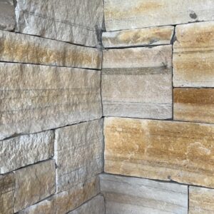 Close-up of a corner featuring stacked stone wall with varying shades of gray and light brown.