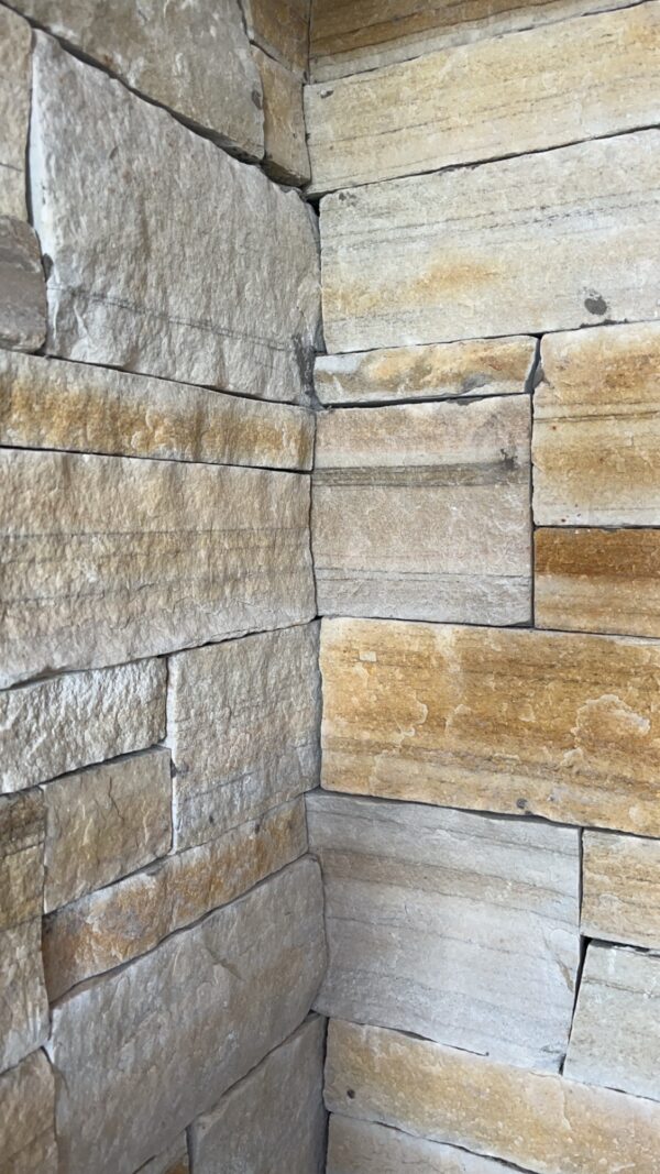 Close-up of a corner featuring stacked stone wall with varying shades of gray and light brown.