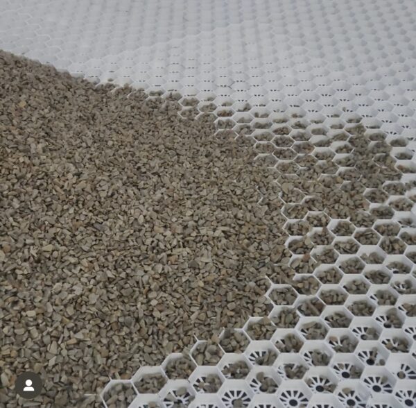 A close-up view of a surface featuring small gray gravel spread over a white, honeycomb-patterned base.