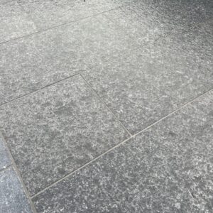 Close-up of textured gray stone tiles with a polished surface, arranged in a geometric pattern.