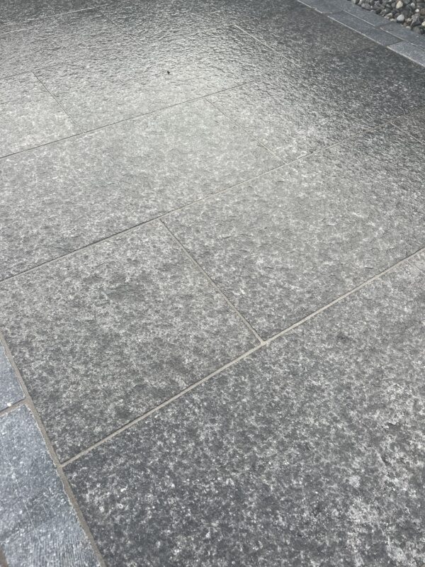 Close-up of textured gray stone tiles with a polished surface, arranged in a geometric pattern.