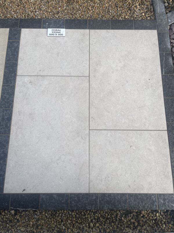 A surface of light-colored coral stone tiles, measuring 600 x 900, bordered by dark gray stone tiles, with small pebbles visible in the background.