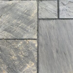 A textured surface of gray stone tiles with varying shades and patterns, arranged in a haphazard manner.